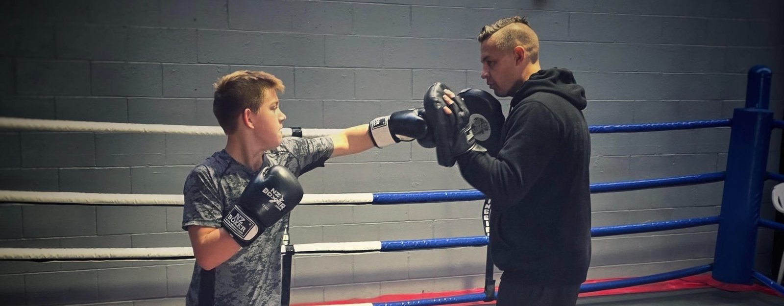 Zac Schultz throwing a jab onto the pads with his boxing coach in the ring