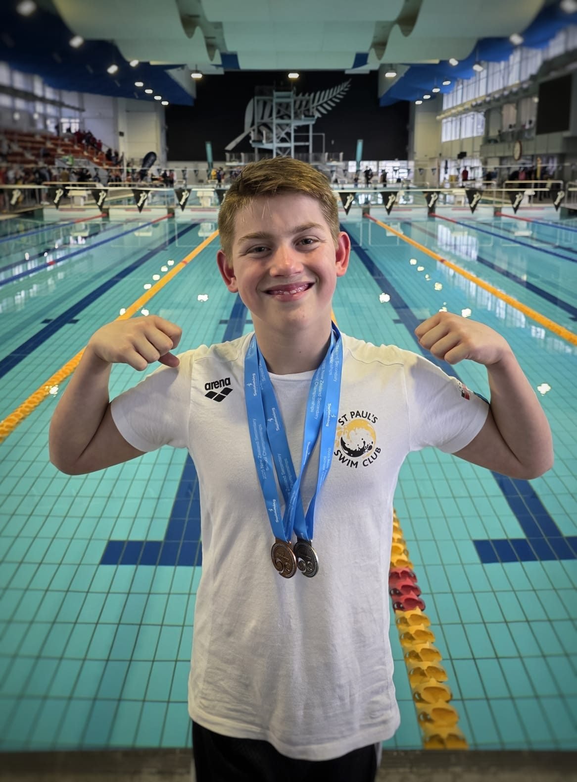Zac Schultz holding up two medals at the New Zealand Secondary Schools Swimming Championships